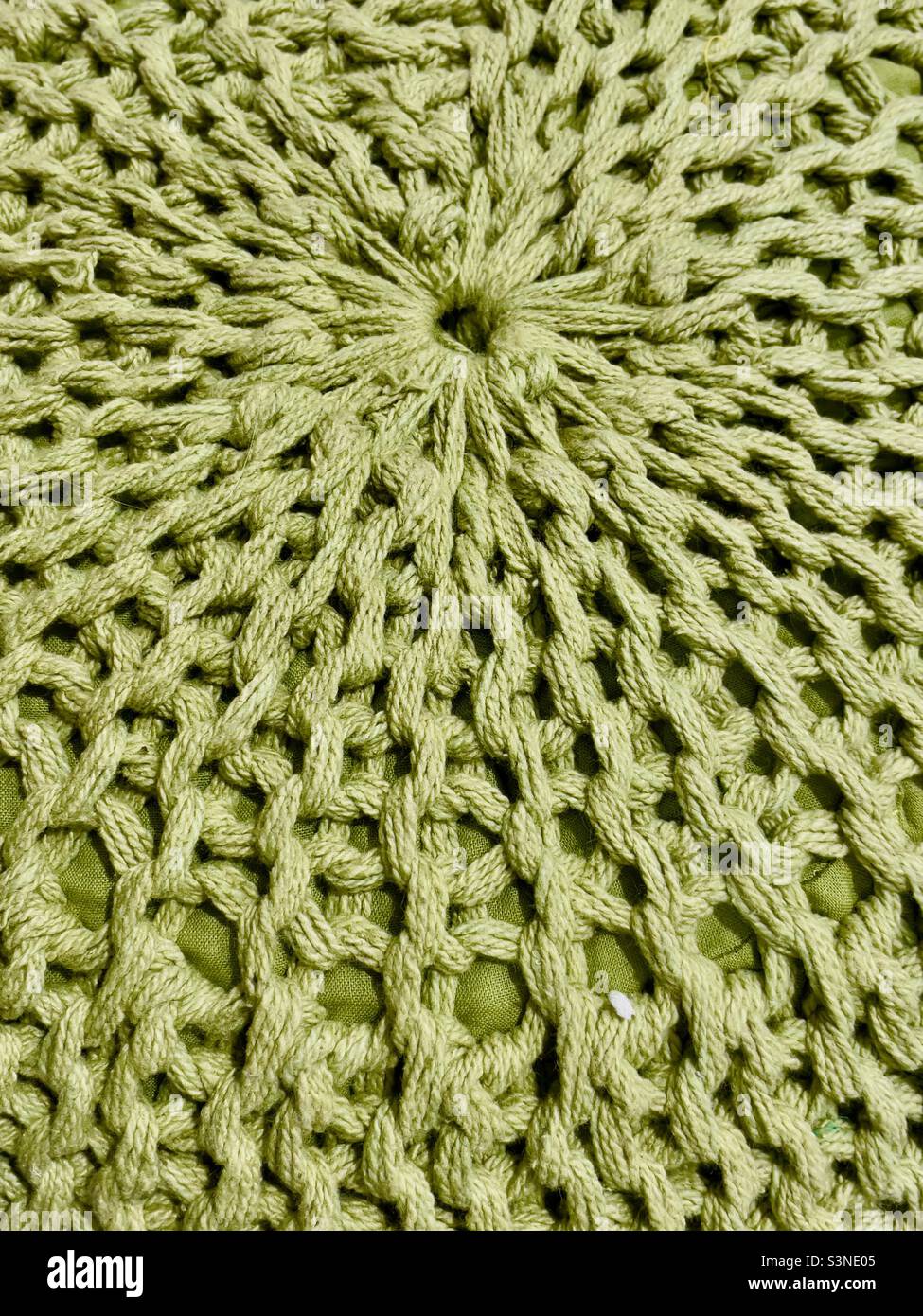 A knitted pouffe in thick green wool exhibiting a radial pattern - Smartphone Captured Stock Image