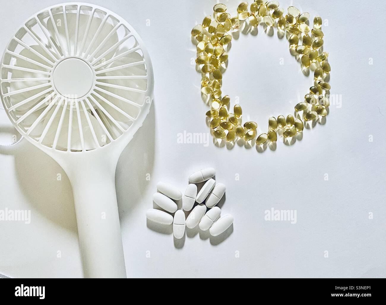 Women’s health and menopause flat lay, portable fan with calcium and vitamin D supplement pills