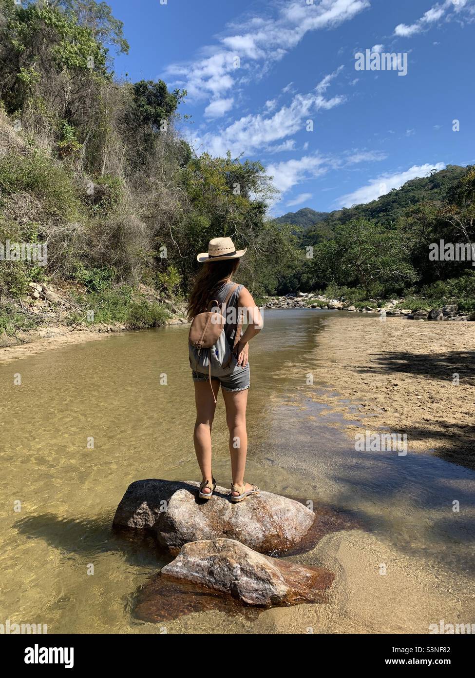 Woman standing on rock with backpack and sombrero - Smartphone Captured Stock Image