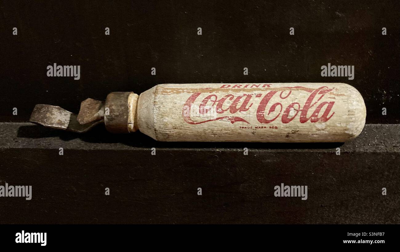 Antique Coca-Cola bottle opener on brown. Stock Photo