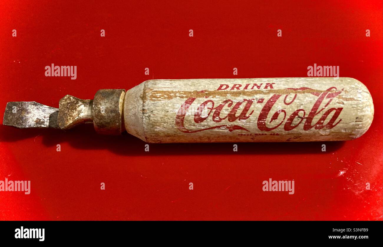 Antique Coca-Cola bottle opener on red. Stock Photo