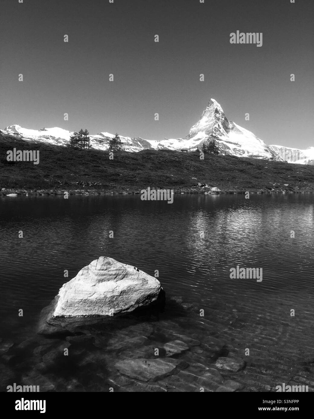 The Matterhorn near Zermatt, Switzerland reflected in a lake. The rock in the foreground mimics the mountain. - Smartphone Captured Stock Image