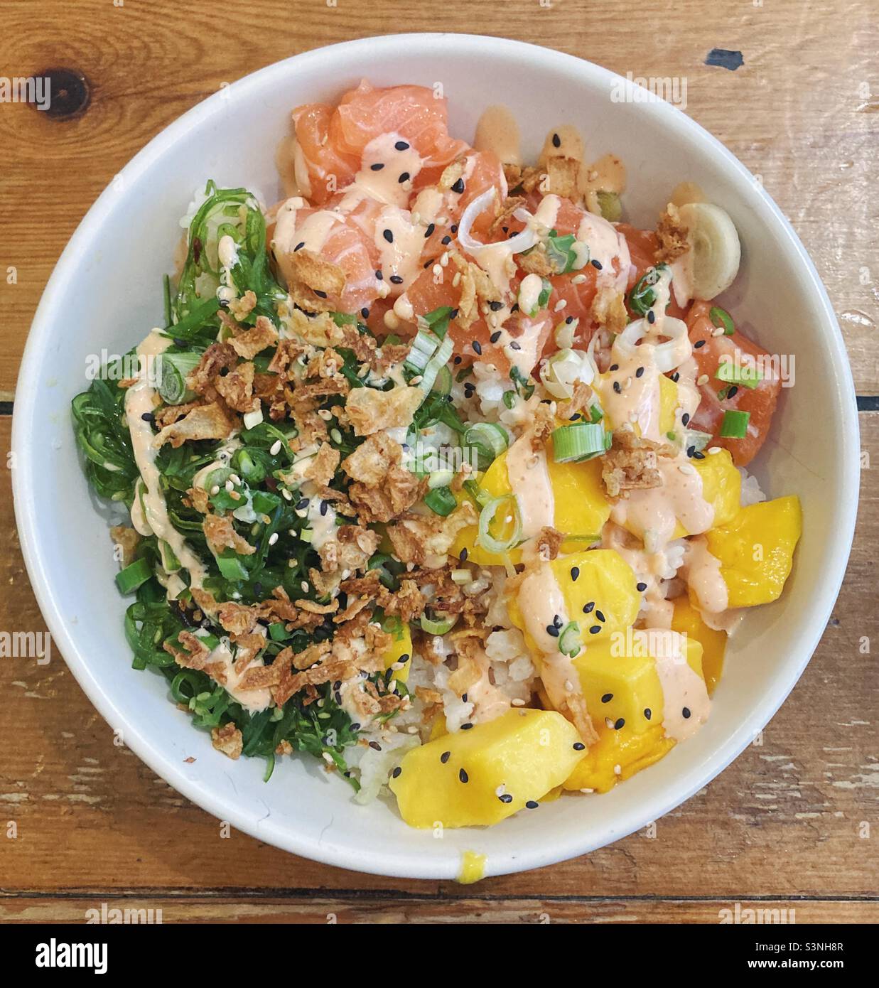 Hawaiian style poke bowl with sushi rice, salmon, mango, seaweed, Sriracha mayonnaise, crispy
