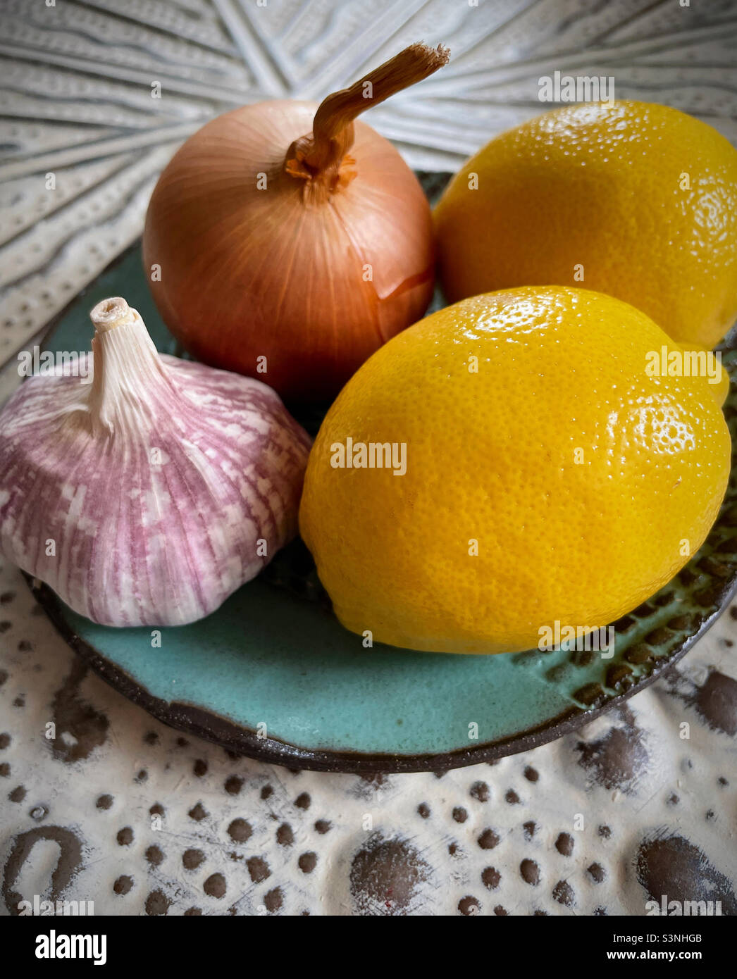 Still life of a plate with two lemons, an onion and a garlic bulb - Smartphone Captured Stock Image