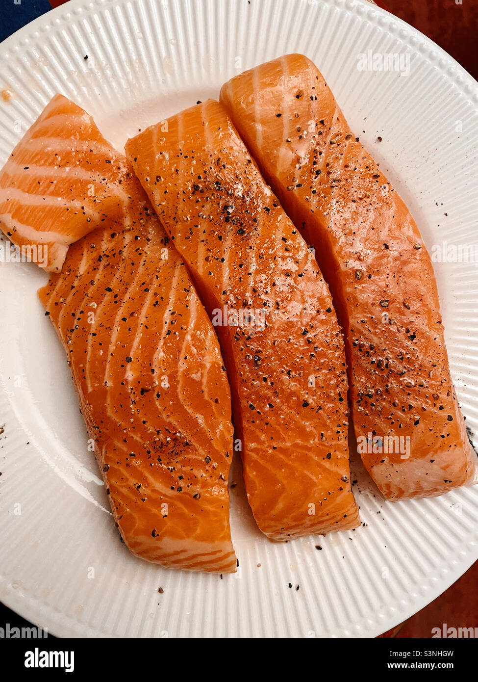 Slices of raw salmon fillet being prepared for grilling, 2022, United States - Smartphone Captured Stock Image