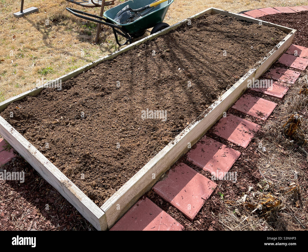 Raised garden bed filled with dirt and cow manure in a backyard Stock