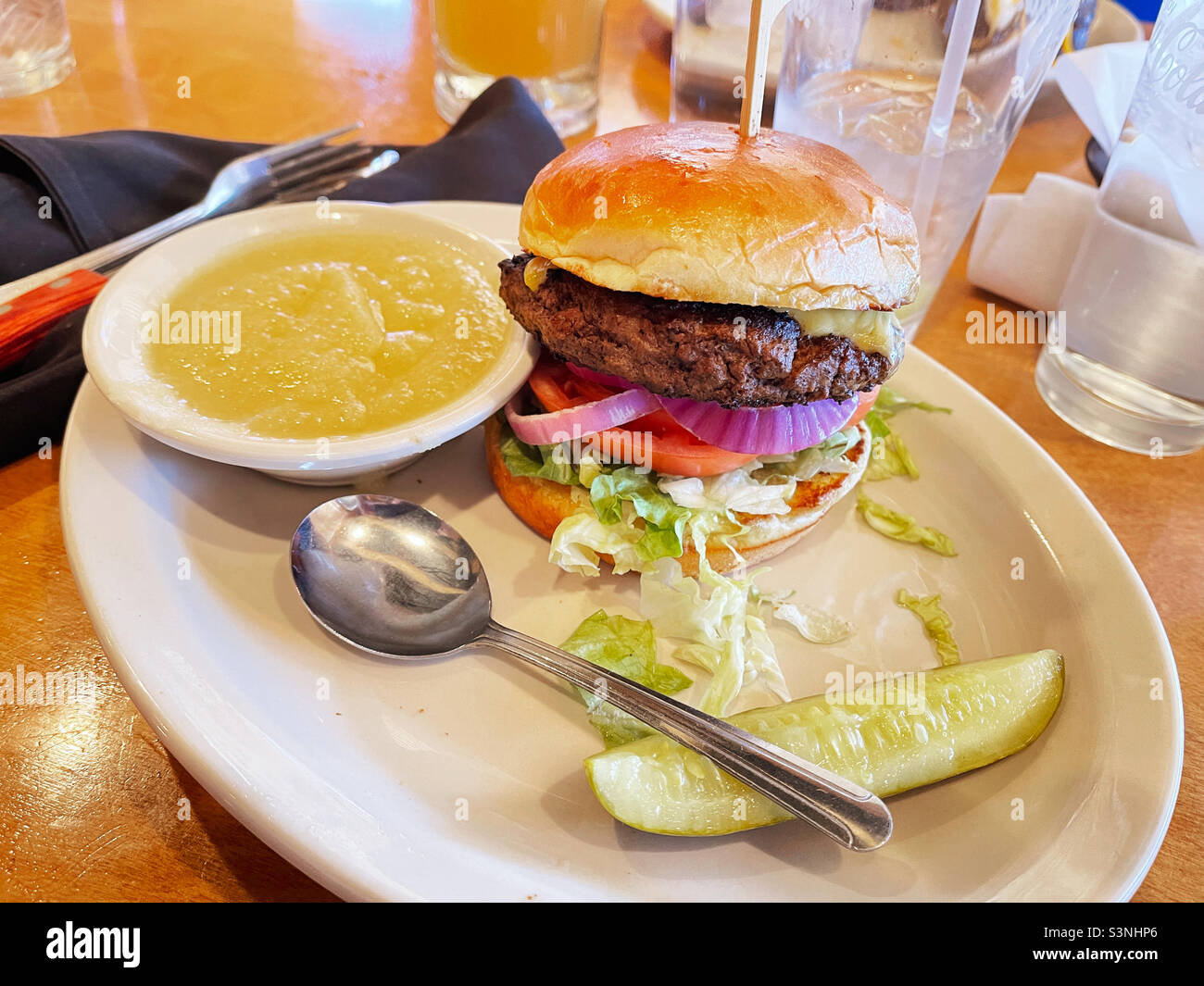 Chargrilled hamburger with all the fixings served with a pickle and applesauce. Stock Photo
