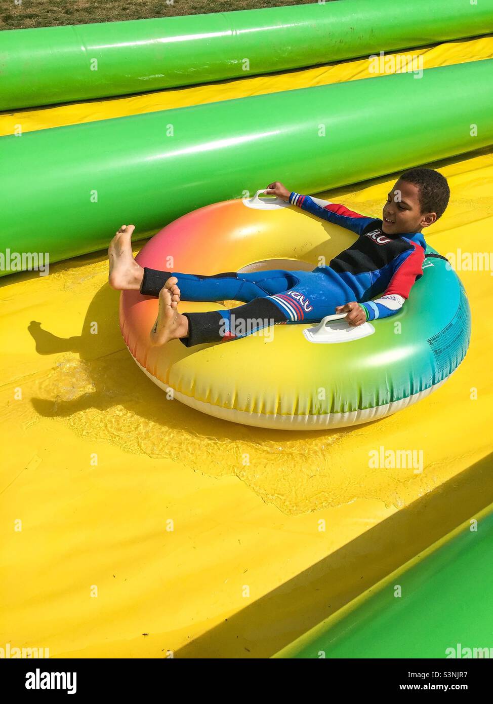 Young boy riding inflatable doughnut on water slide Stock Photo - Alamy