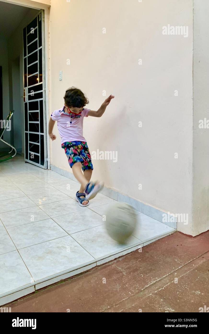 5 year old boy kicks a soccer ball up into the air. Havana, Cuba, Caribbean Stock Photo