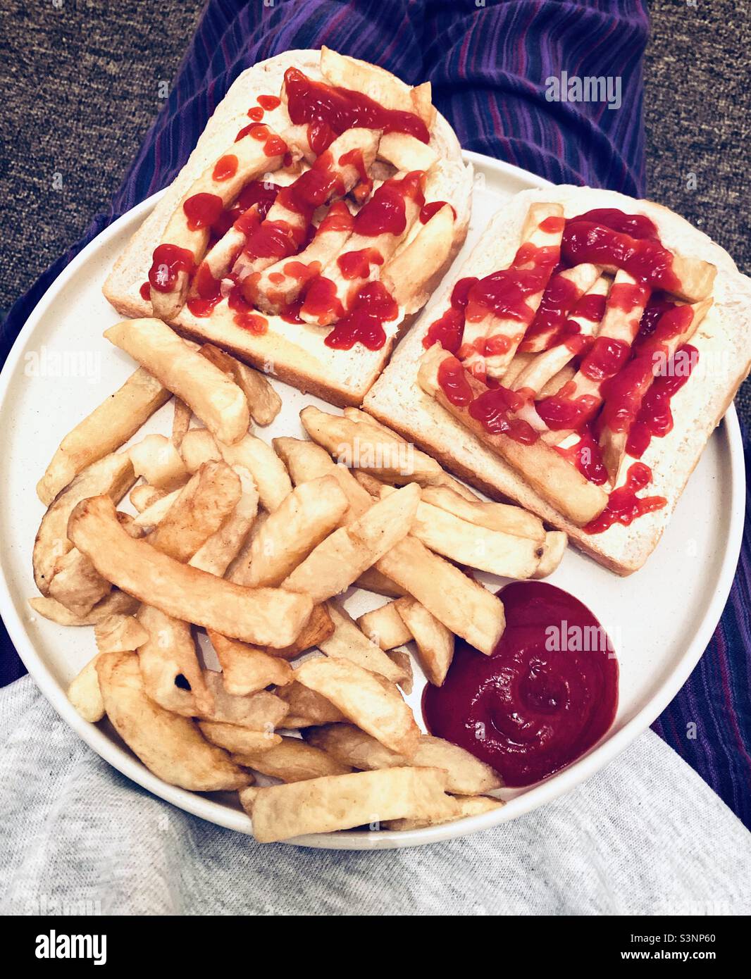 Any Sauce?! Chips and tomato ketchup butty, on a plate, on a lap! Stock Photo