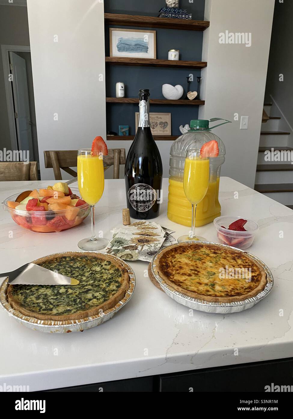 Sunday brunch, quiche, fruit and mimosas on white counter. Stock Photo