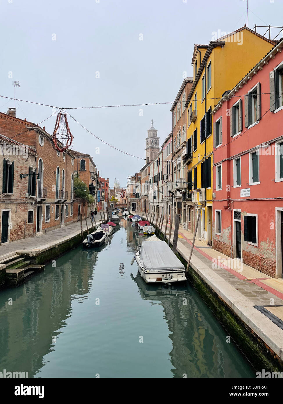 Quiet residential neighborhood in Venice, Italy. Parked boats on a canal surrounded by colourful houses and historic apartment buildings. - Smartphone Captured Stock Image