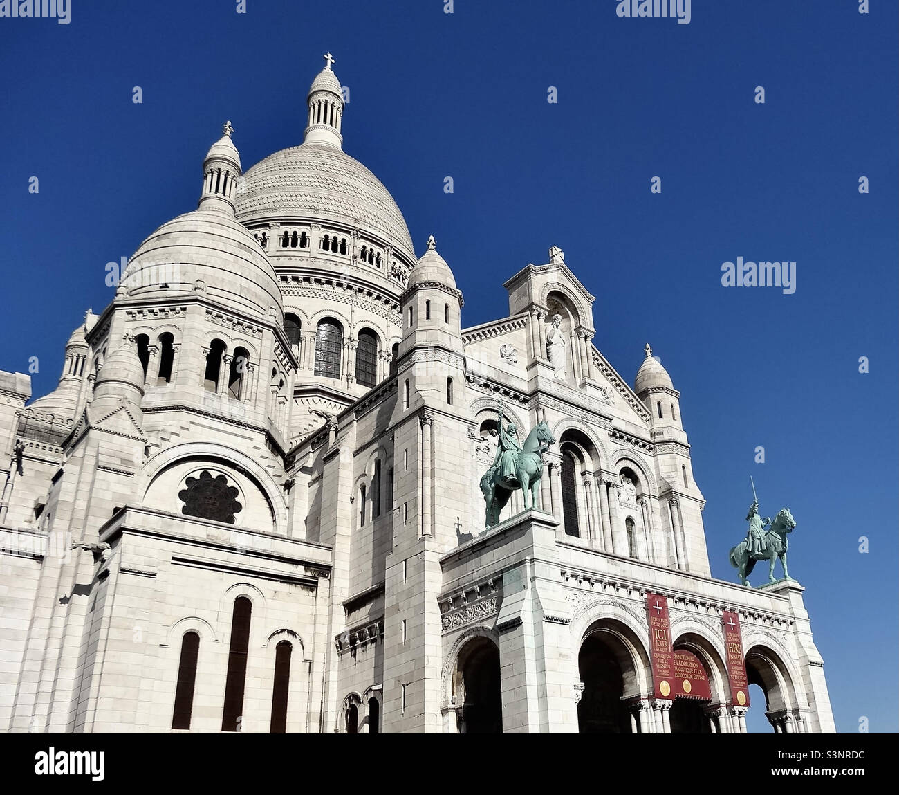 Sacre-Coeur Basilica (1875-1914), Montmartre, Paris, with the statues of Louis IX (L) and Joan of Arc (R). High up at 131m/430ft and with 5 domes, it was built on 83 pillars sunk 40m/131 ft deep. Stock Photo