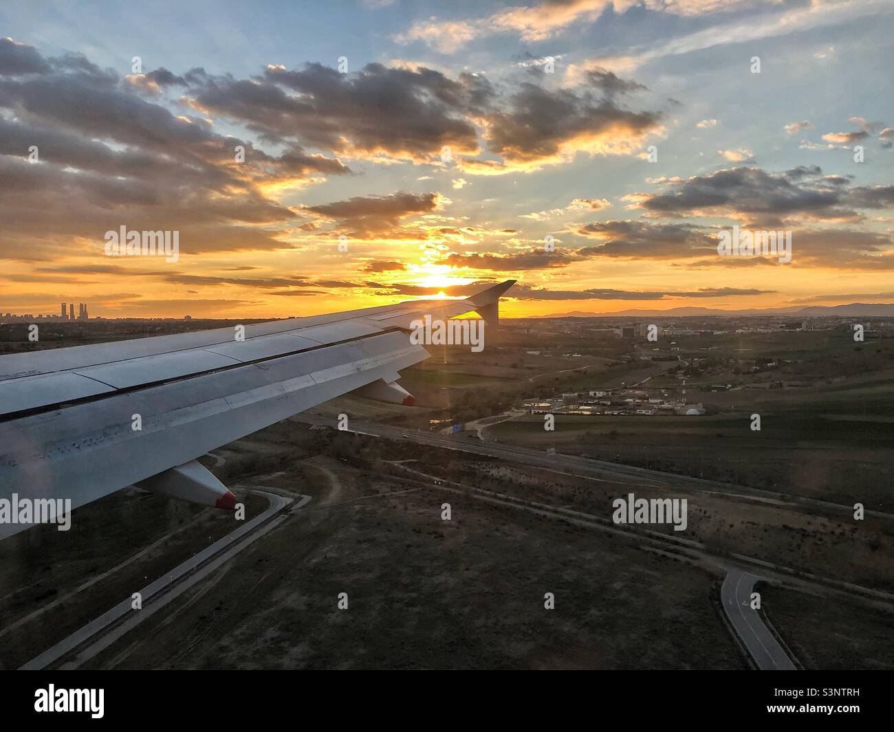 Wing of a plane landing in Madrid at sunset - Smartphone Captured Stock Image