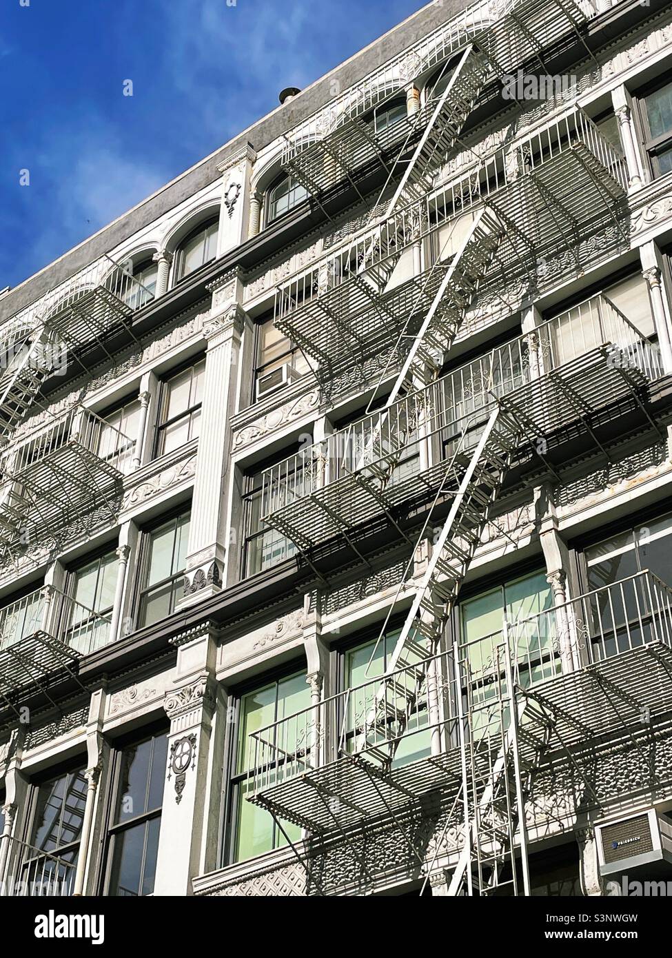 Cast iron façade and fire escapes on a building in Soho, New York City, United States - Smartphone Captured Stock Image