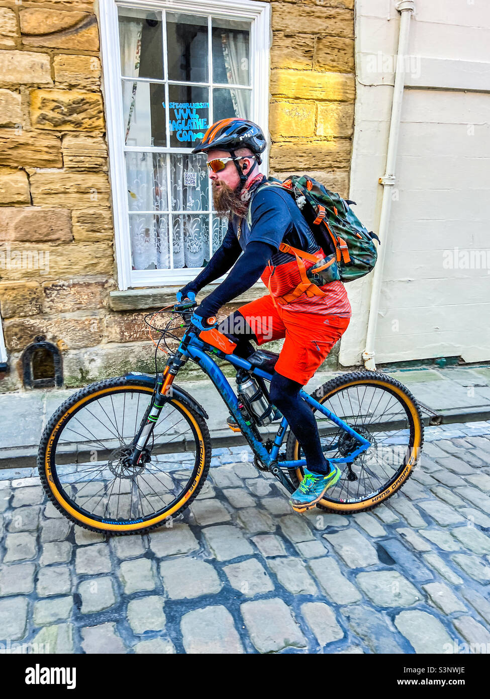 Cyclist riding bicycle on cobbled street in Whitby - Smartphone Captured Stock Image