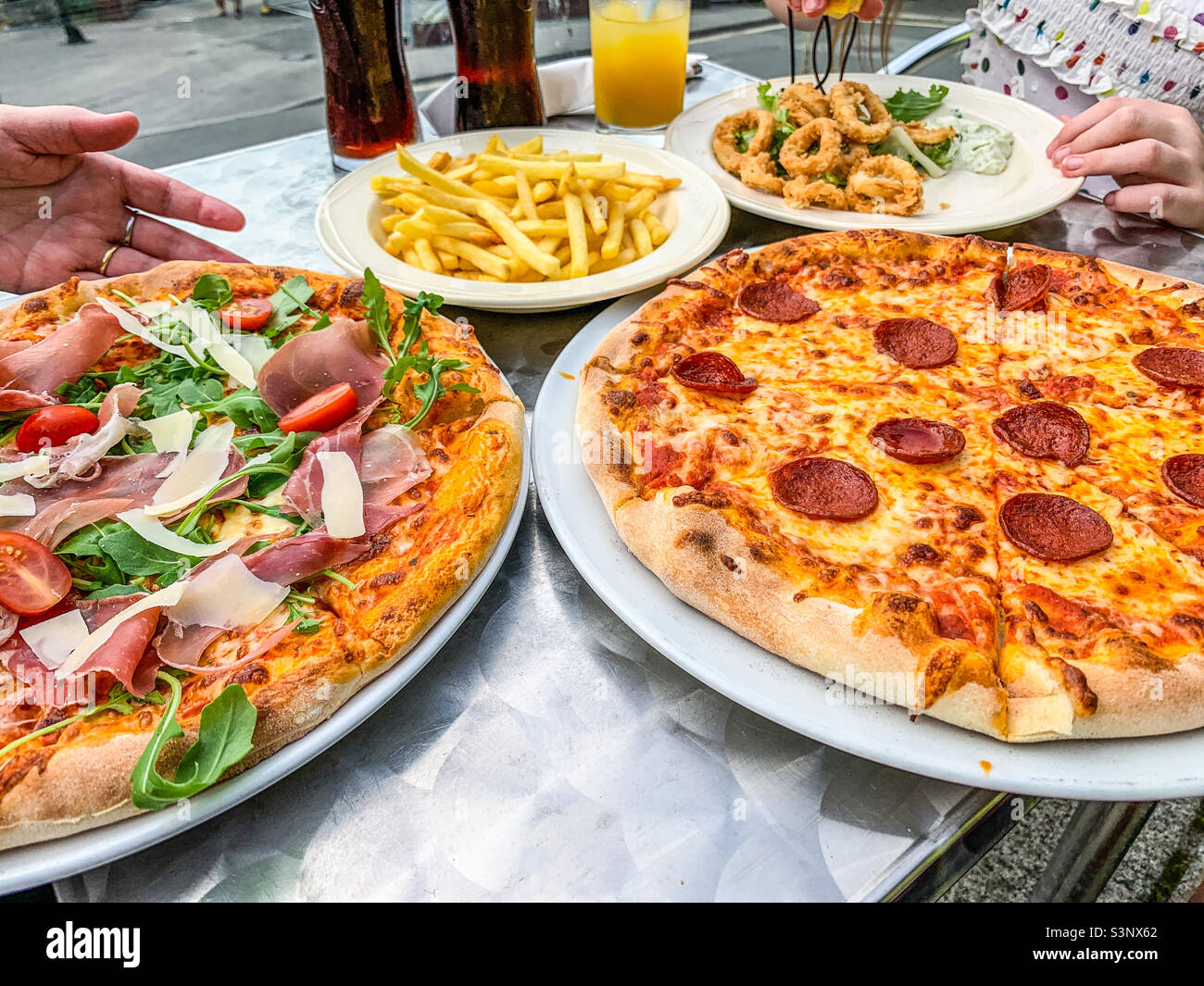Pizzas fries and calamari served in outside restaurant Stock Photo