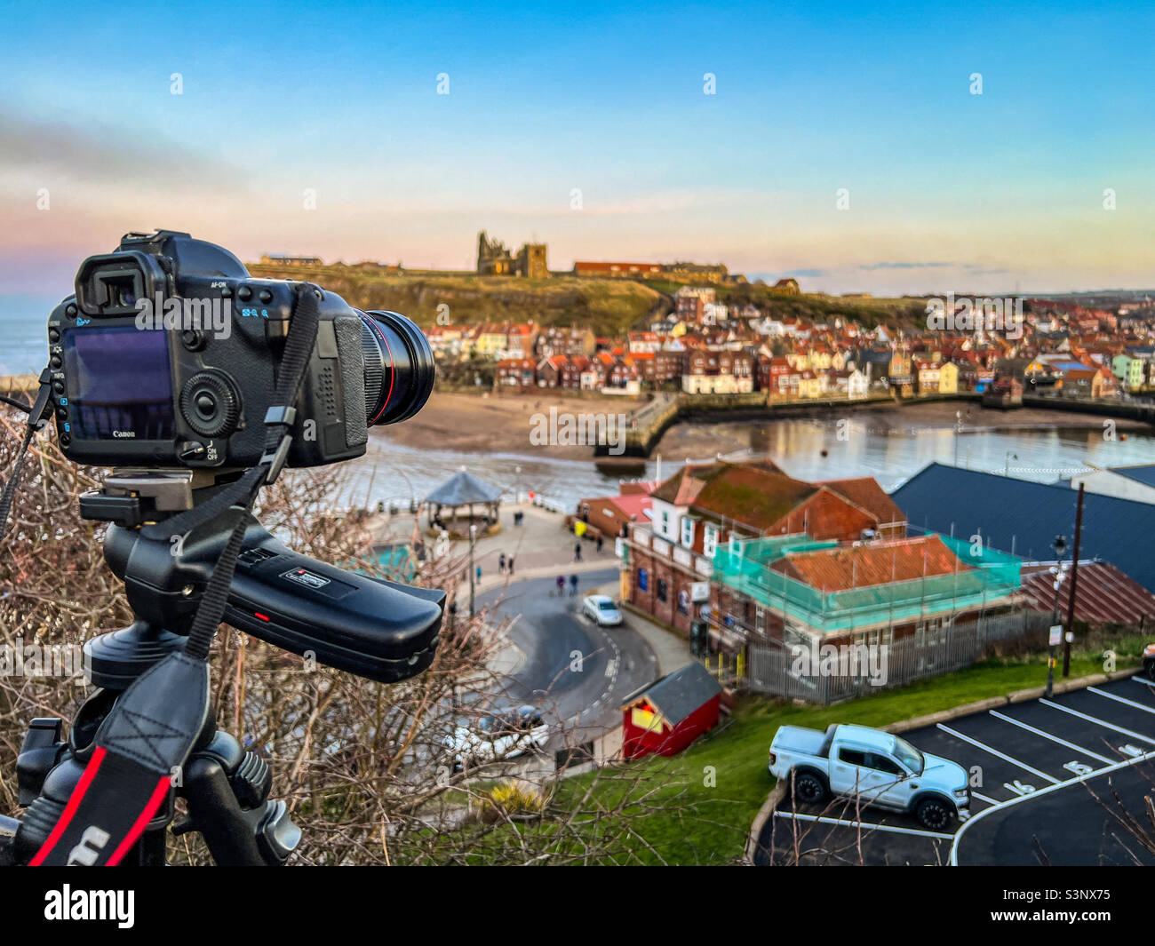 Professional photographer taking photos with canon digital slr camera of Whitby at dusk - Smartphone Captured Stock Image