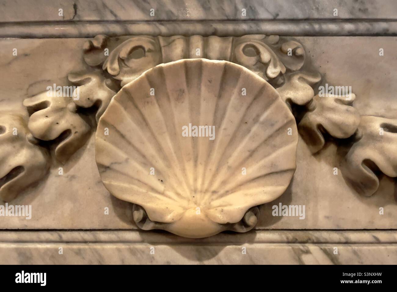 A scallop shell in carved marble flanked by two swags of classical husks, a detail of a fireplace in a Sussex country house hotel. - Smartphone Captured Stock Image