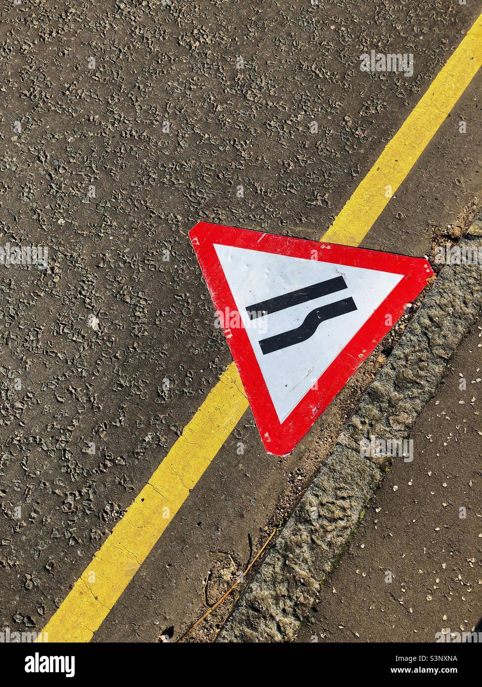 Road sign, road narrows on right, fallen in kerb - Smartphone Captured Stock Image