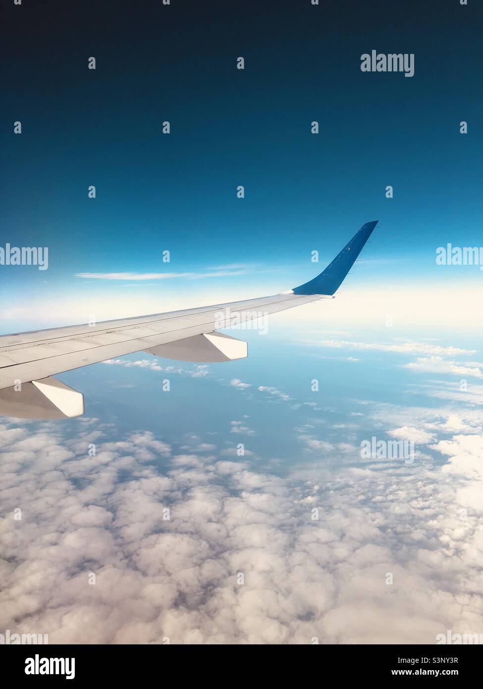Airplane wing seen from inside. Flying above the clouds in the Caribbean sea. Havana, Cuba. - Smartphone Captured Stock Image