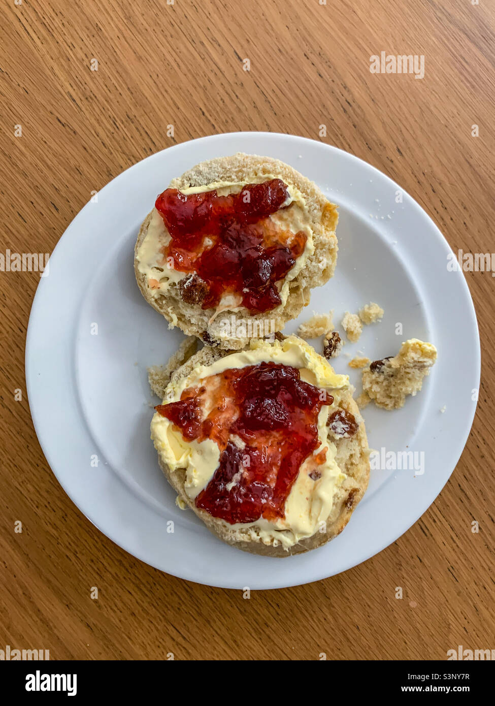 Fruit scone with clotted cream and strawberry jam on white plate - Smartphone Captured Stock Image
