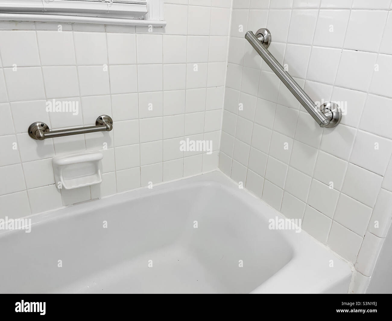 Newly installed handicap grip and grab bars in a ceramic tiled bathtub ...
