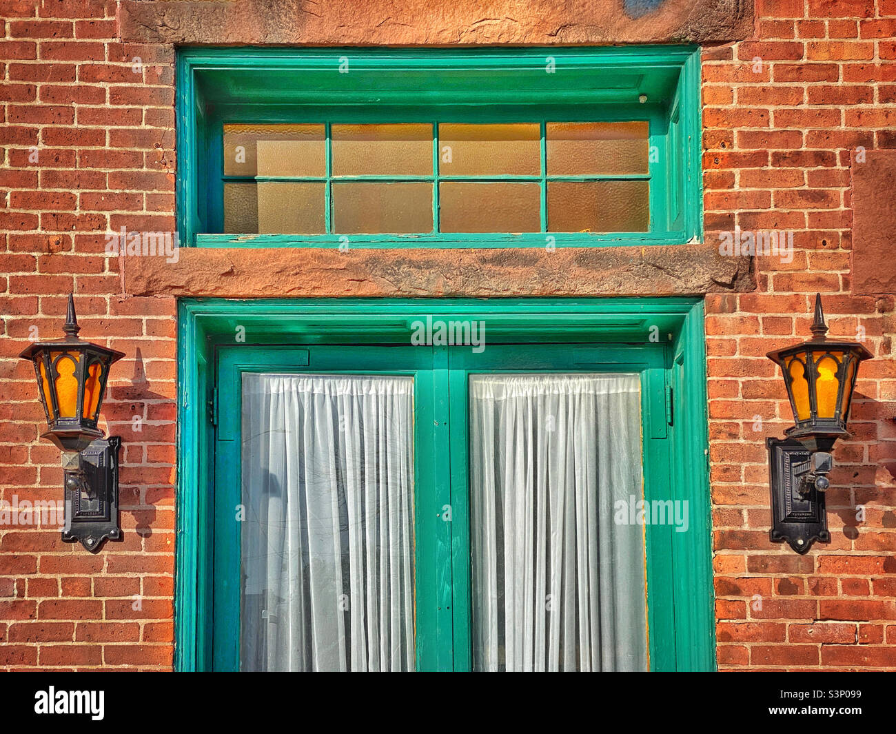 Old fashioned wall lanterns beside a green door - Smartphone Captured Stock Image