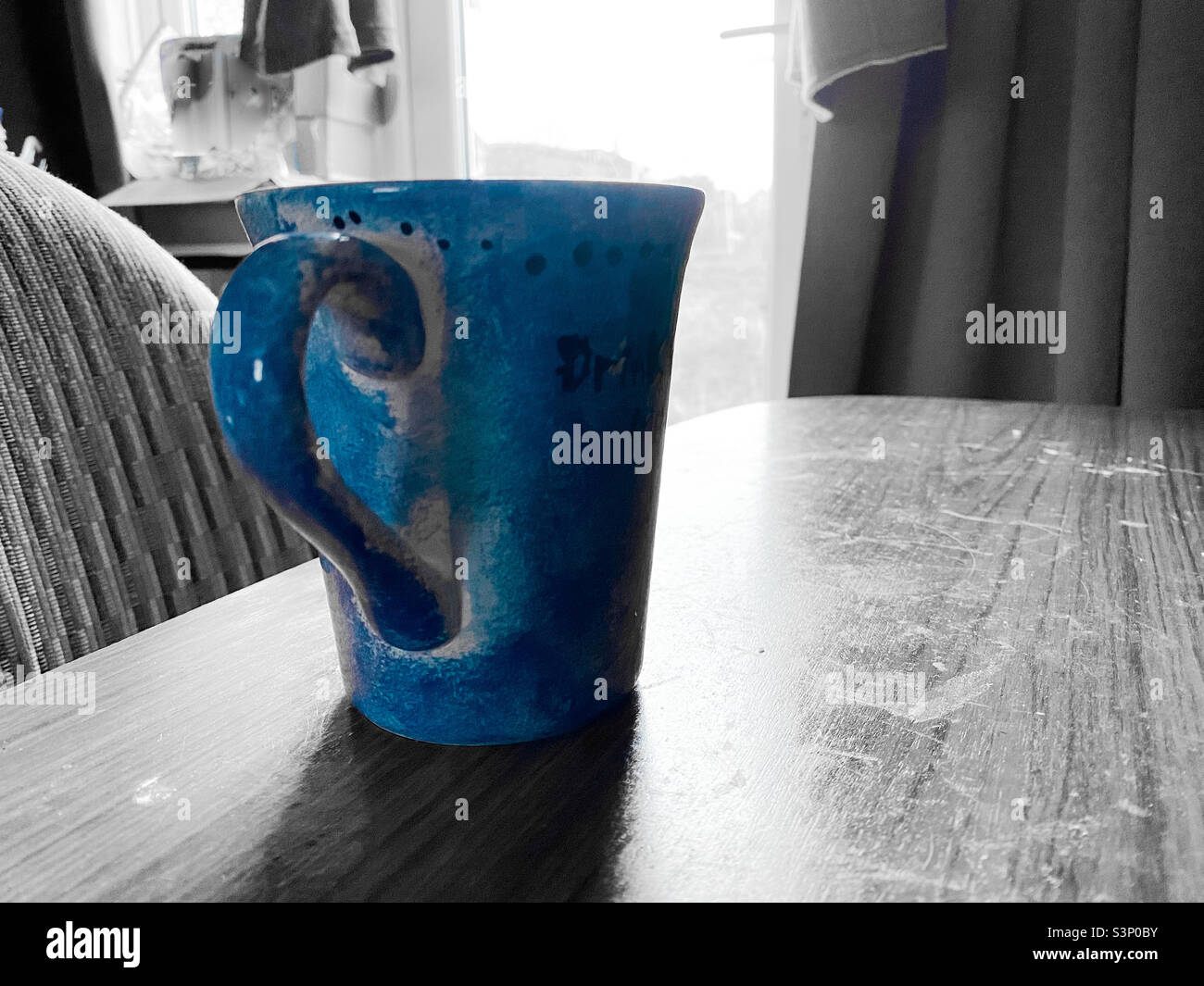 Morning mug of tea on a table with all colours but blue desaturated. - Smartphone Captured Stock Image