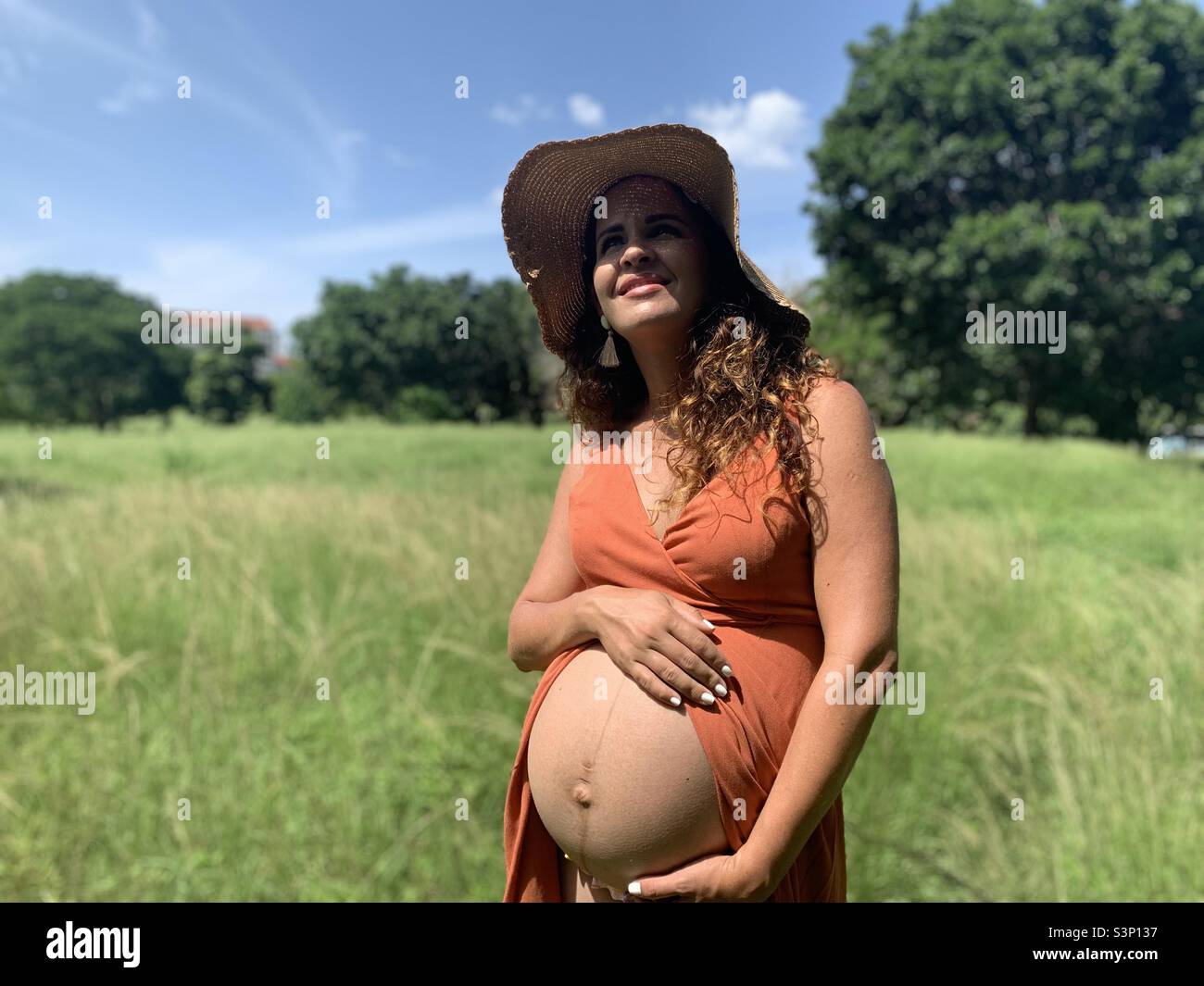 8 Month pregnant woman holding her belly. Linea nigra visible Stock Photo