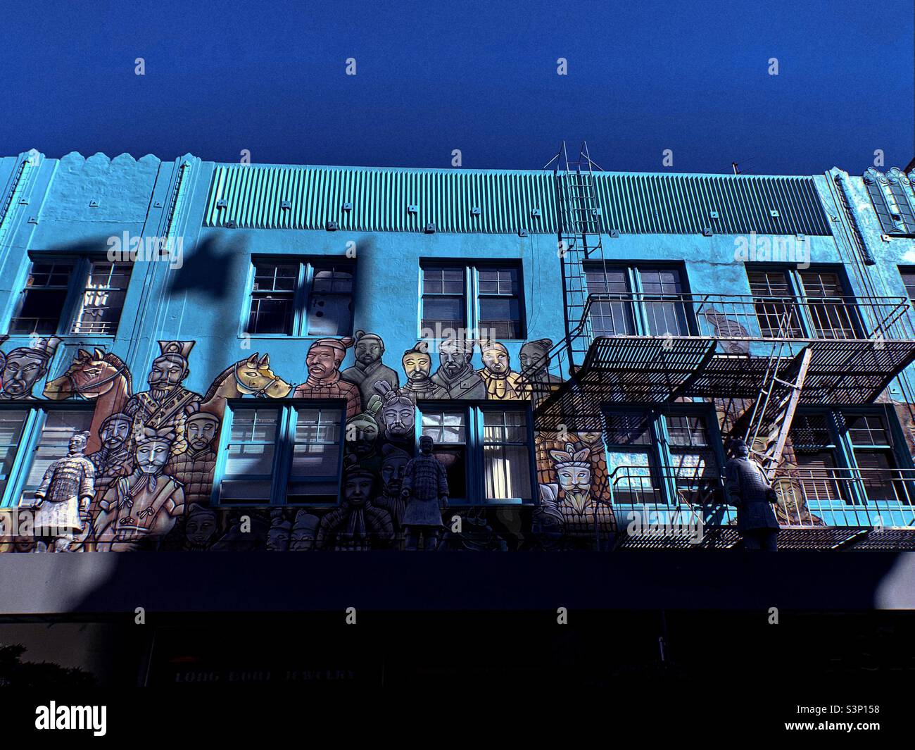 The drawing of the Chinese traditional figures on the two-stories San Francisco Chinatown old building under the blue and cloudless sky. Stock Photo
