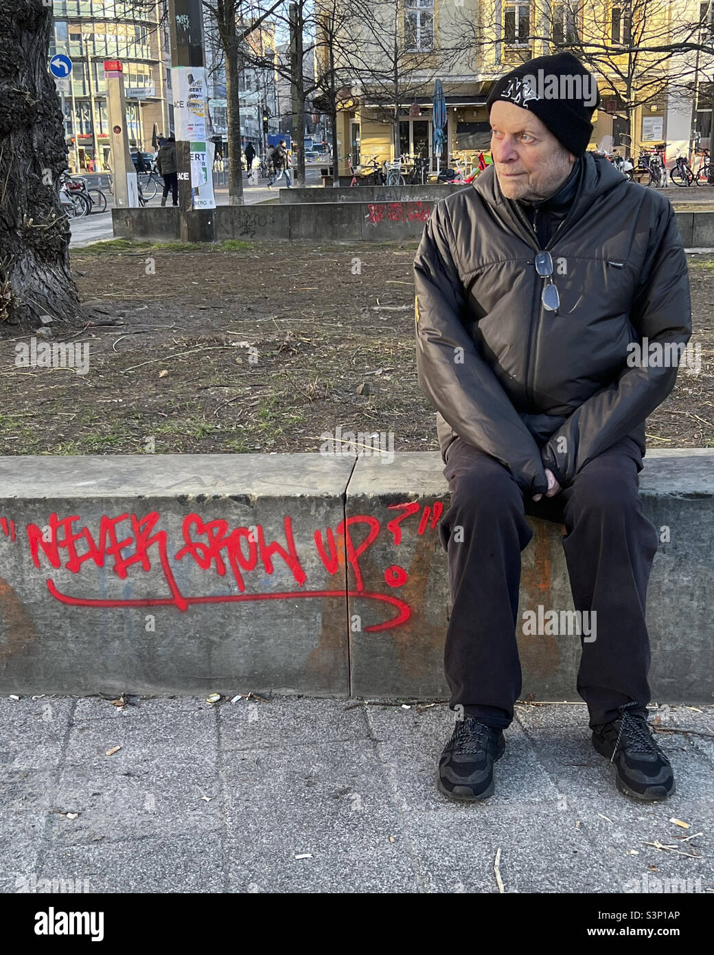 Elderly man sitting on bench & Never Grow Up graffiti - Mitte, Berlin, Germany - Smartphone Captured Stock Image