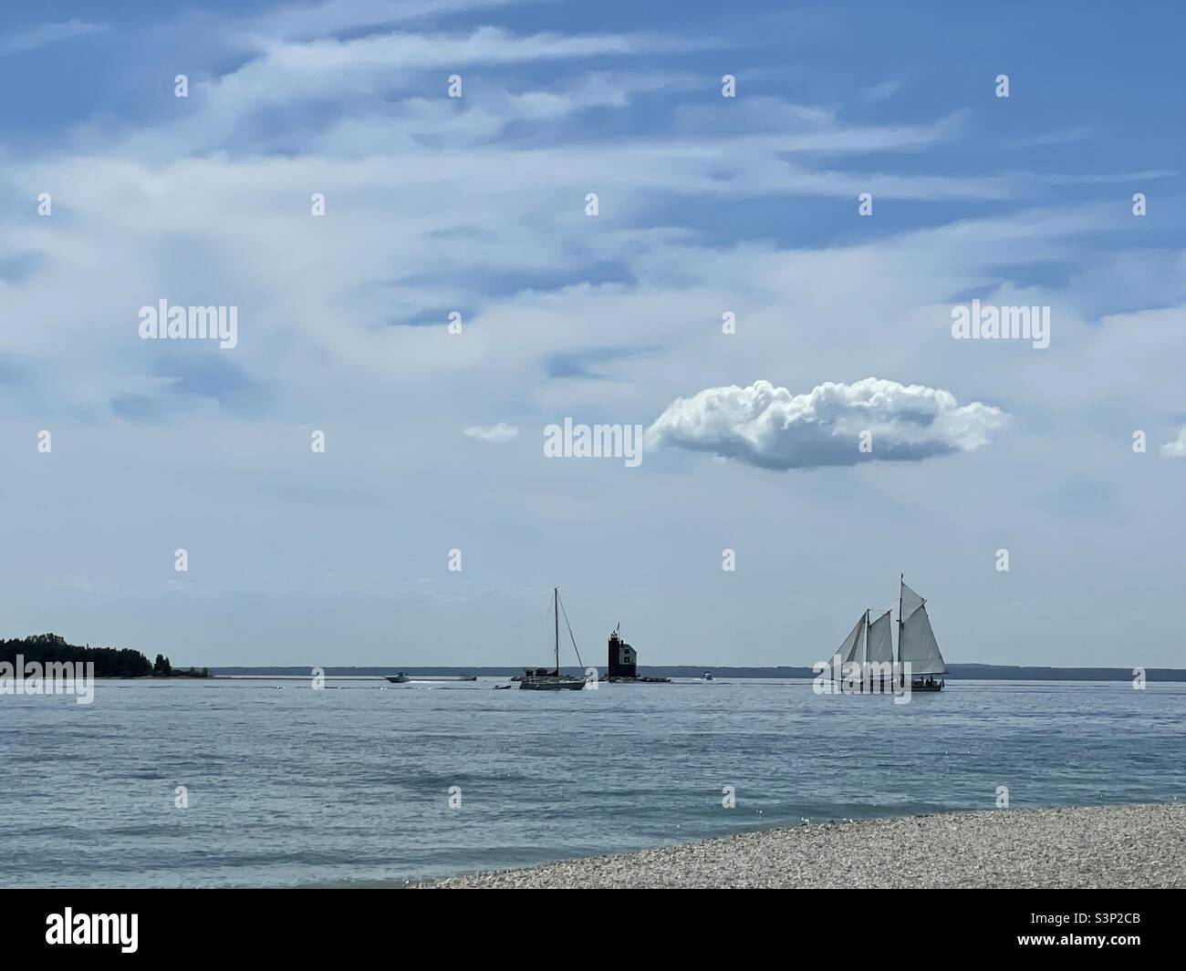 Schooner and lighthouse with big, fluffy cloud overhead - Smartphone Captured Stock Image