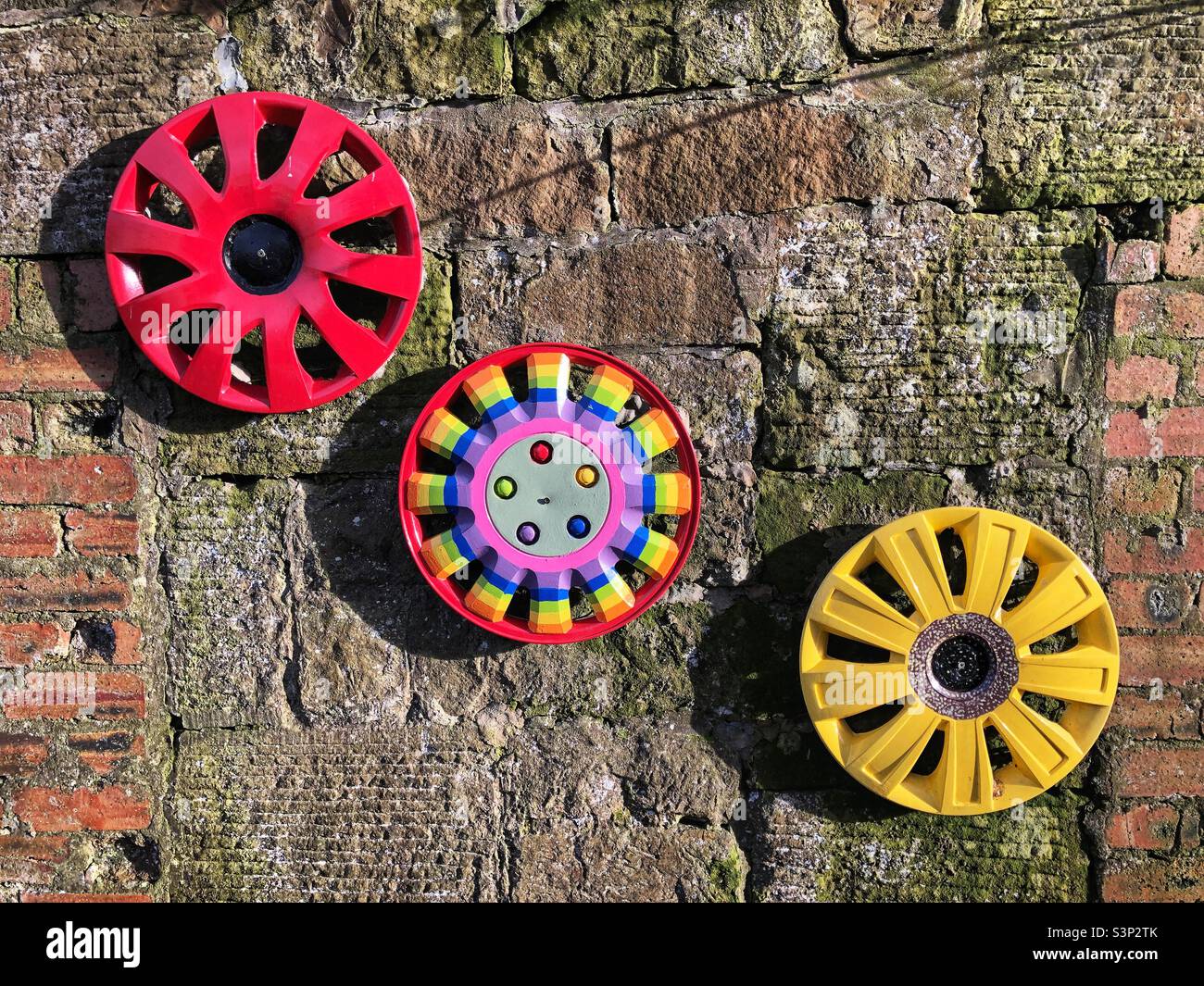 Painted car hubcaps in an outdoor childrens garden Stock Photo