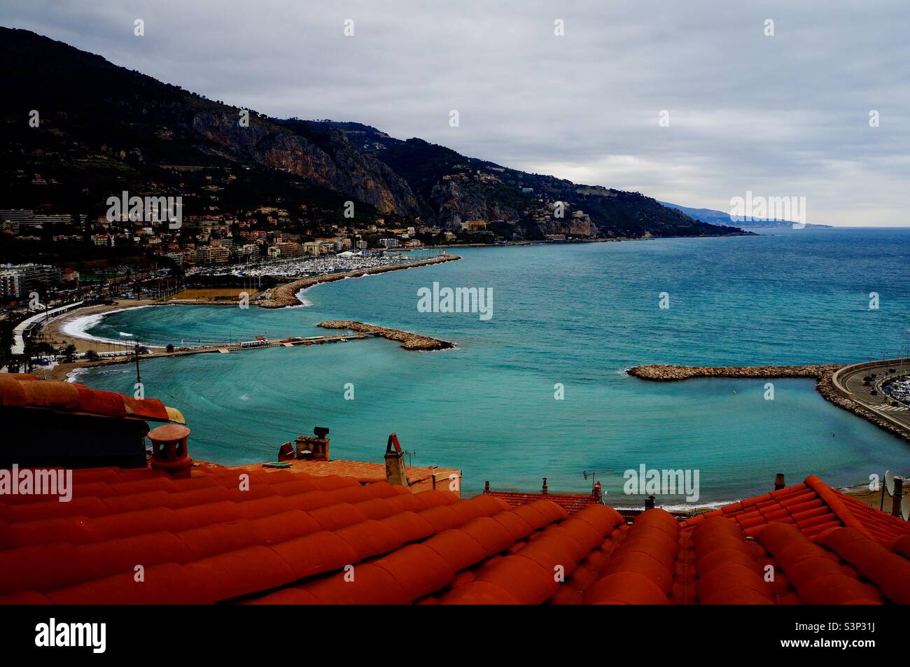 Red clay rooftop slabs against the green Mediterranean Ocean, the bay in Menton France. - Smartphone Captured Stock Image