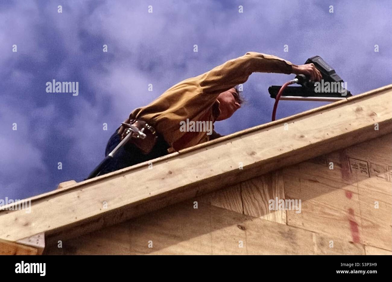 Construction worker Builder working on roof of house Stock Photo
