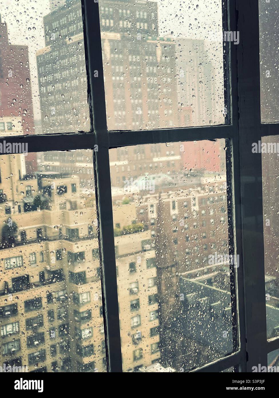 Midtown Manhattan during a rain storm as seen through a casement window in a high-rise apartment in Murray Hill, 2022, NYC, USA - Smartphone Captured Stock Image