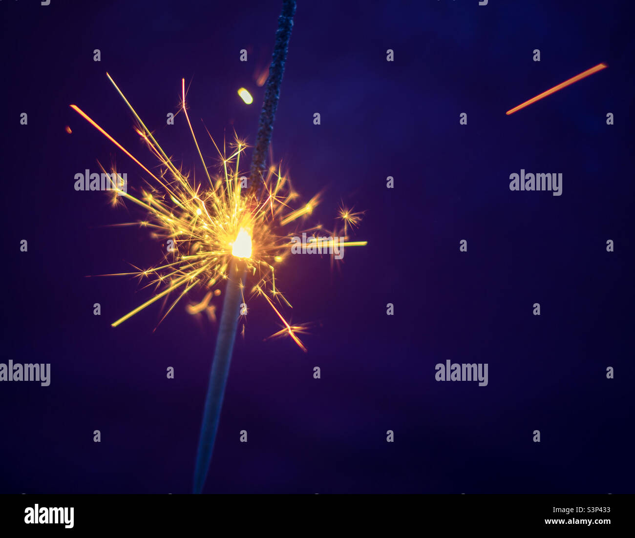 Bright yellow sparkler burning, against purple background - Smartphone Captured Stock Image