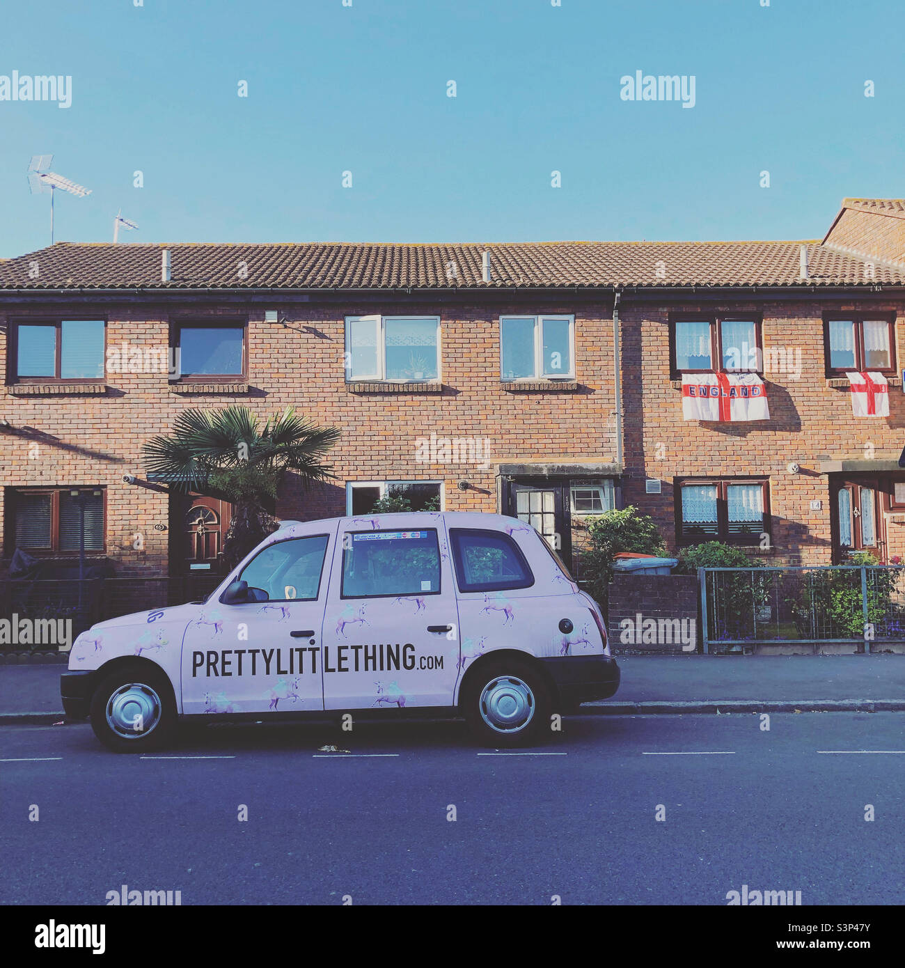 Pink car on the street in East London; England flags hanging from the