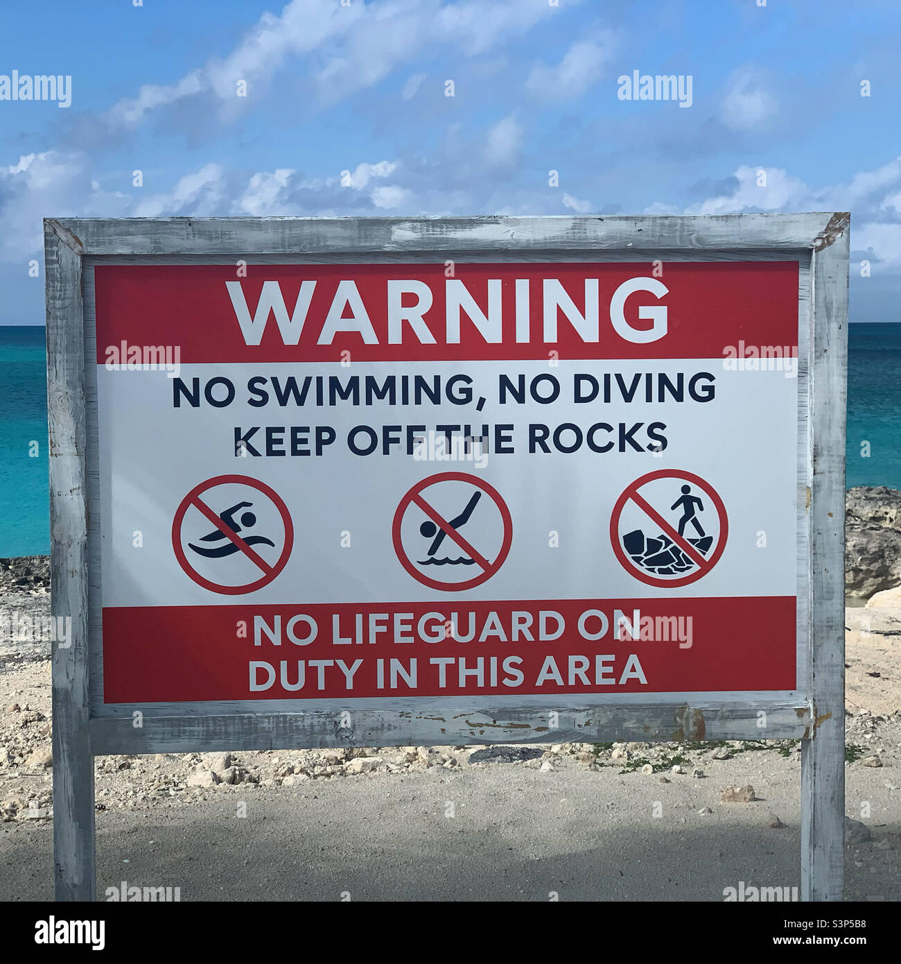 “Warning” sign, “No swimming, no diving. Keep off the rocks. No lifeguards on duty in this area.” - Smartphone Captured Stock Image