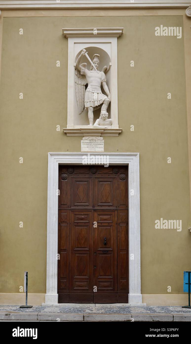 The central door to the Basilica of Saint Michael Archangel with a statue of Saint Michel slaying the devil. - Smartphone Captured Stock Image