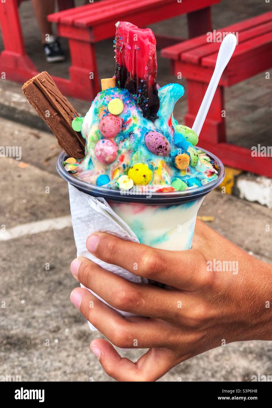Hand holding a delicious and colourful ice cream cup with a chocolate flake and marshmallows - Smartphone Captured Stock Image Hand holding a delicious and colourful ice cream cup with a chocolate flake and marshmallows - Smartphone Captured Stock Image