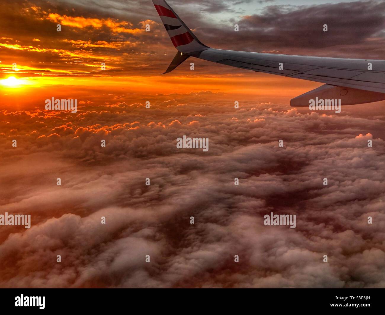 Above the fluffy clouds in an aeroplane and amazing orange sunset - Smartphone Captured Stock Image