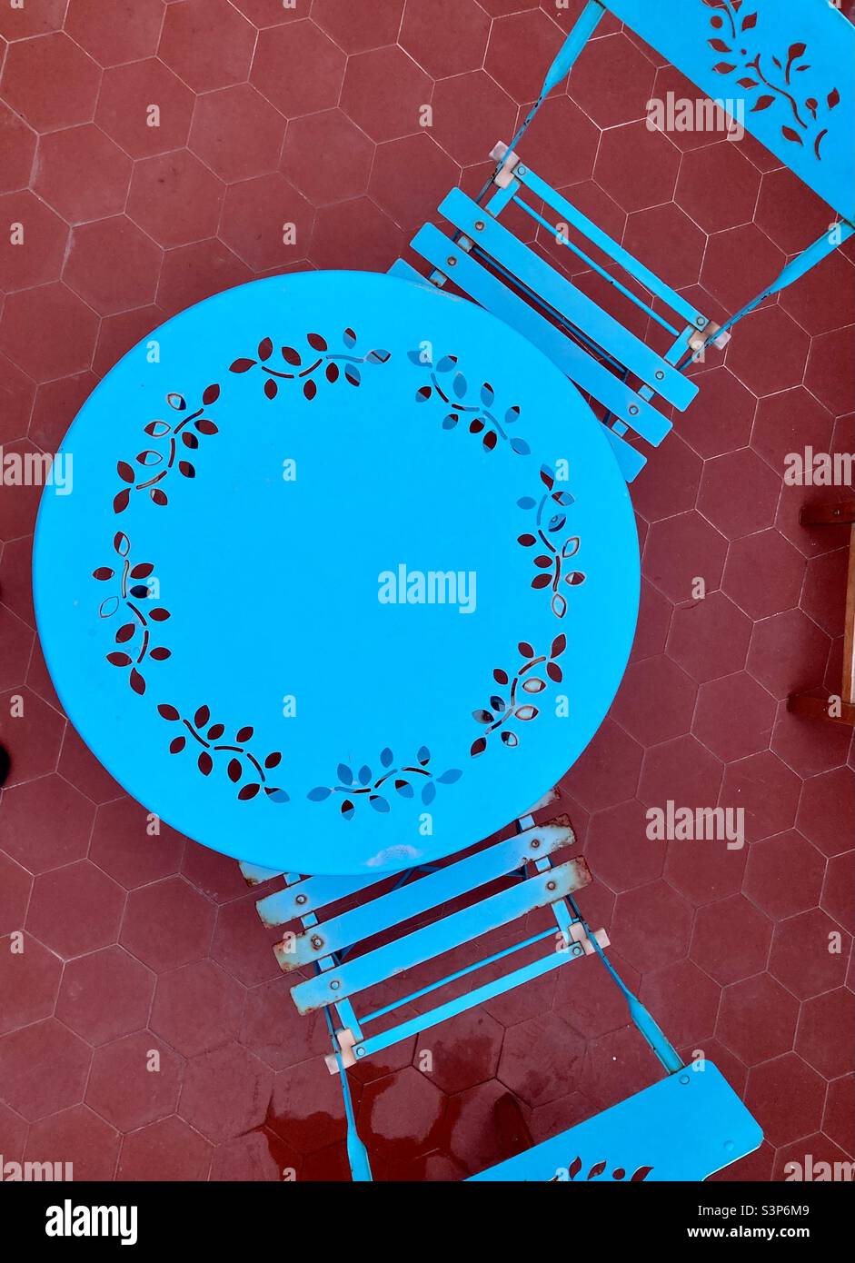 Colour contrast, blue garden set on an red brick floor. - Smartphone Captured Stock Image