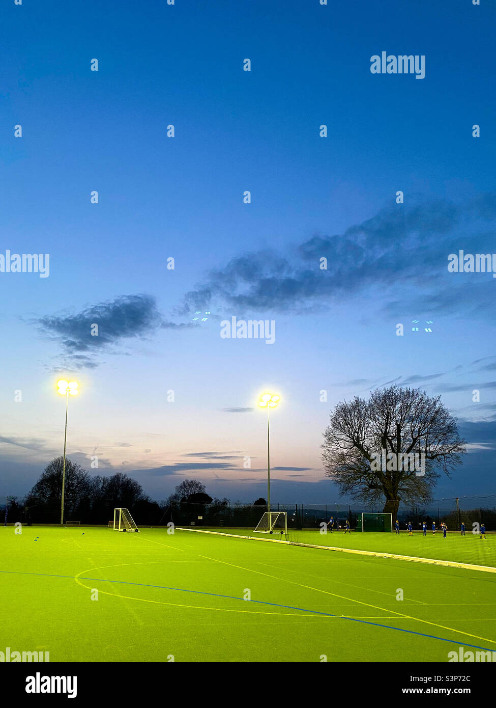 Astro pitch lit by floodlights in early evening. - Smartphone Captured Stock Image