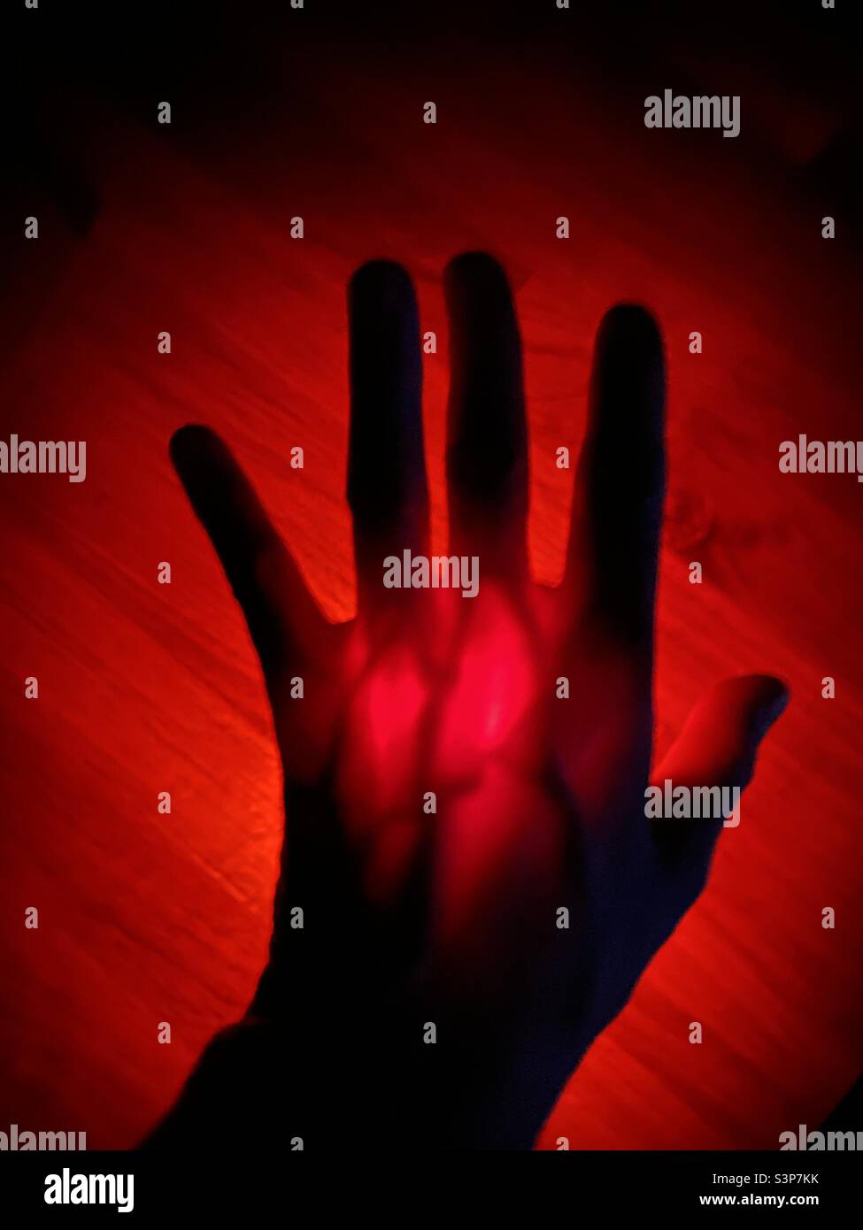 Flashlight shining trough a hand making it red - Smartphone Captured Stock Image