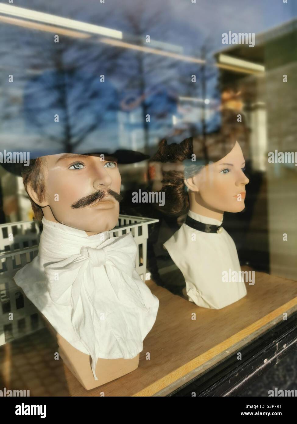mannequins heads with wig in window with trees reflection Stock Photo