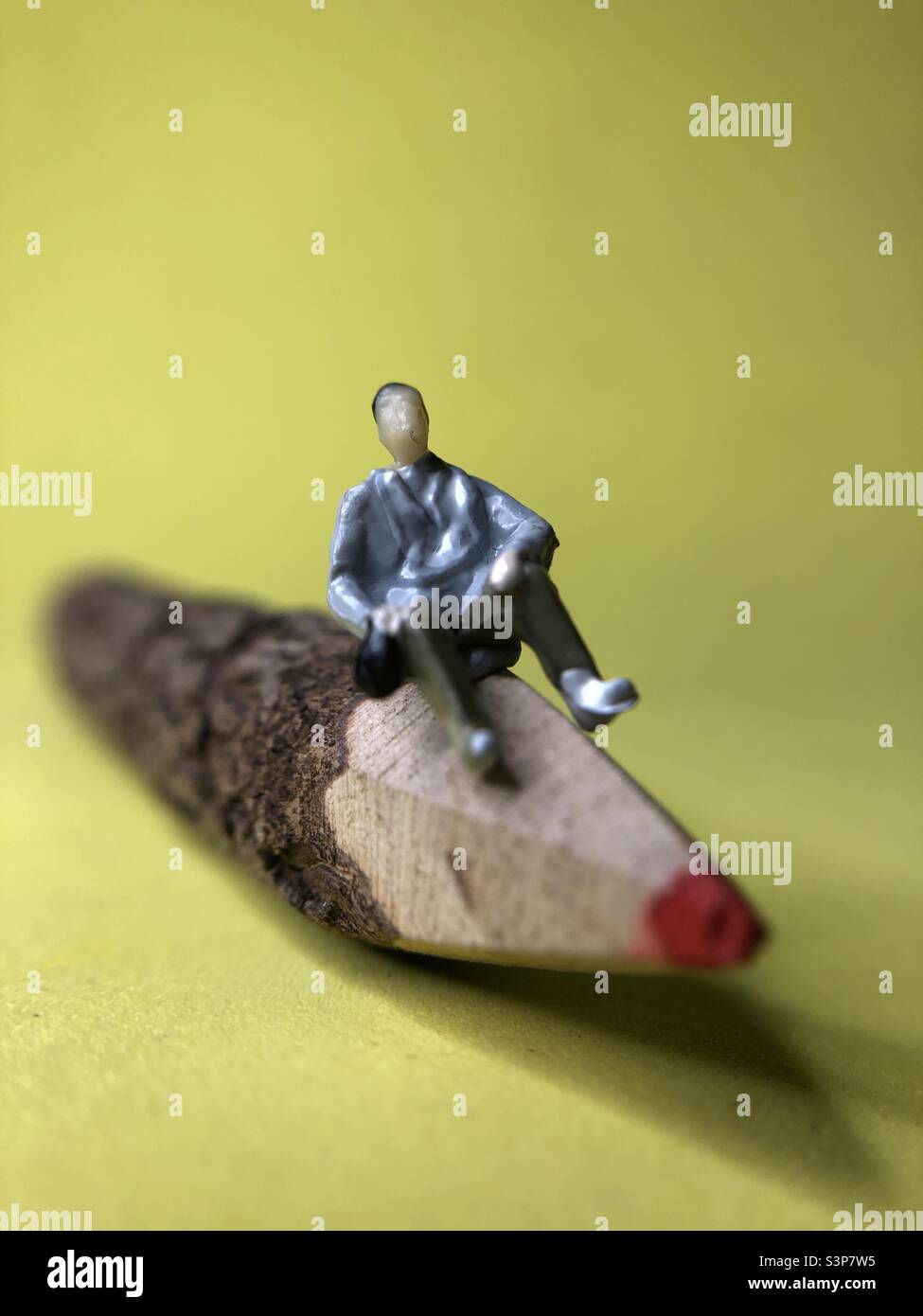 Tiny model person sits on the end of a twig pencil - Smartphone Captured Stock Image