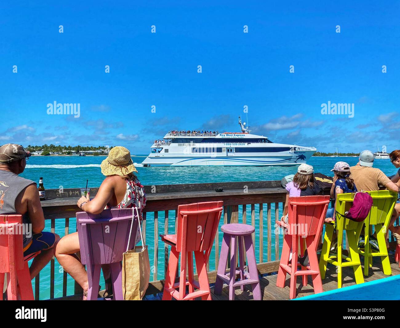 Tourists having drinks while watching boats pass by in Key West Florida Stock Photo