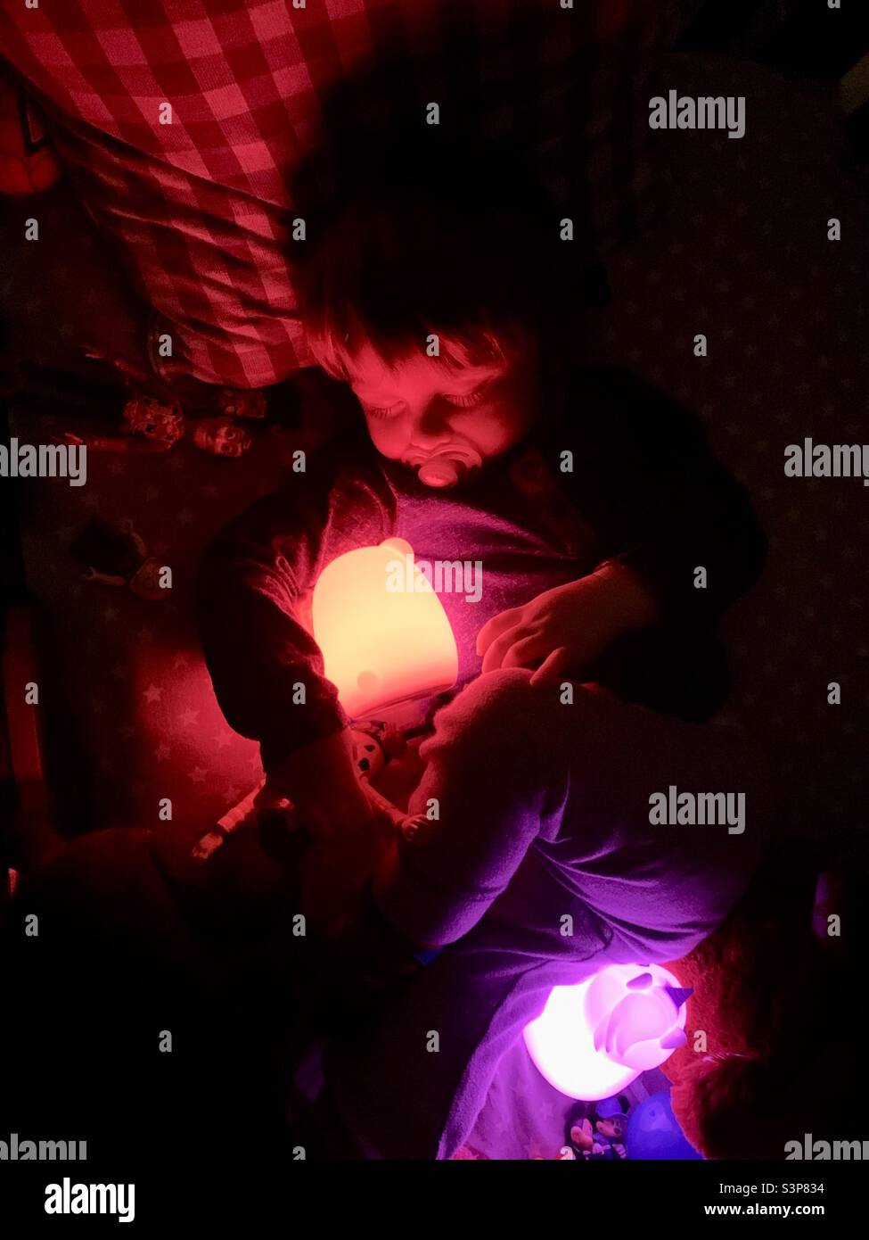 Sleeping toddler with glowing colorful nightlights. Stock Photo